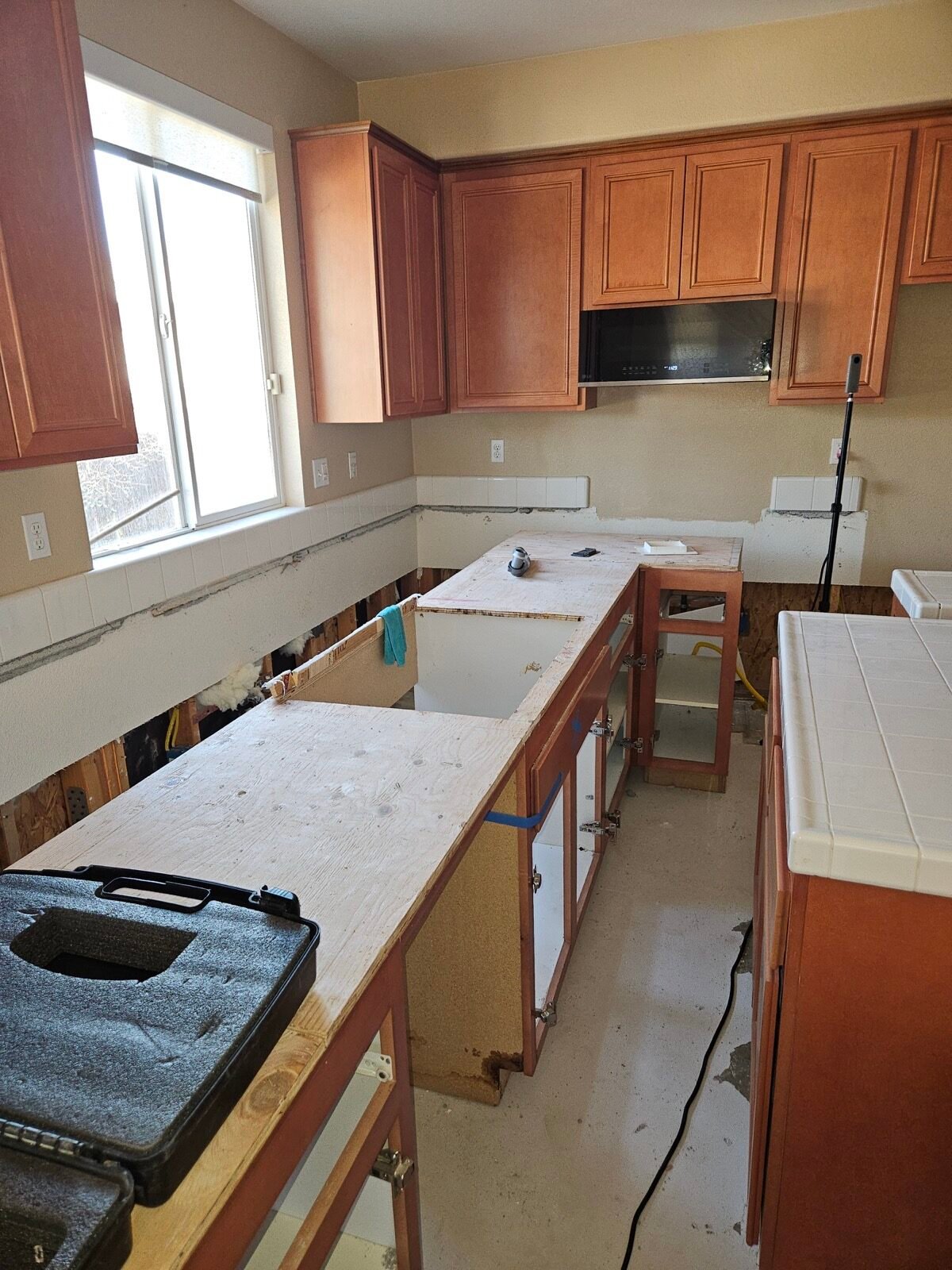 Kitchen cabinets pulled away from an opened lower wall during water-damage work in Santa Nella.